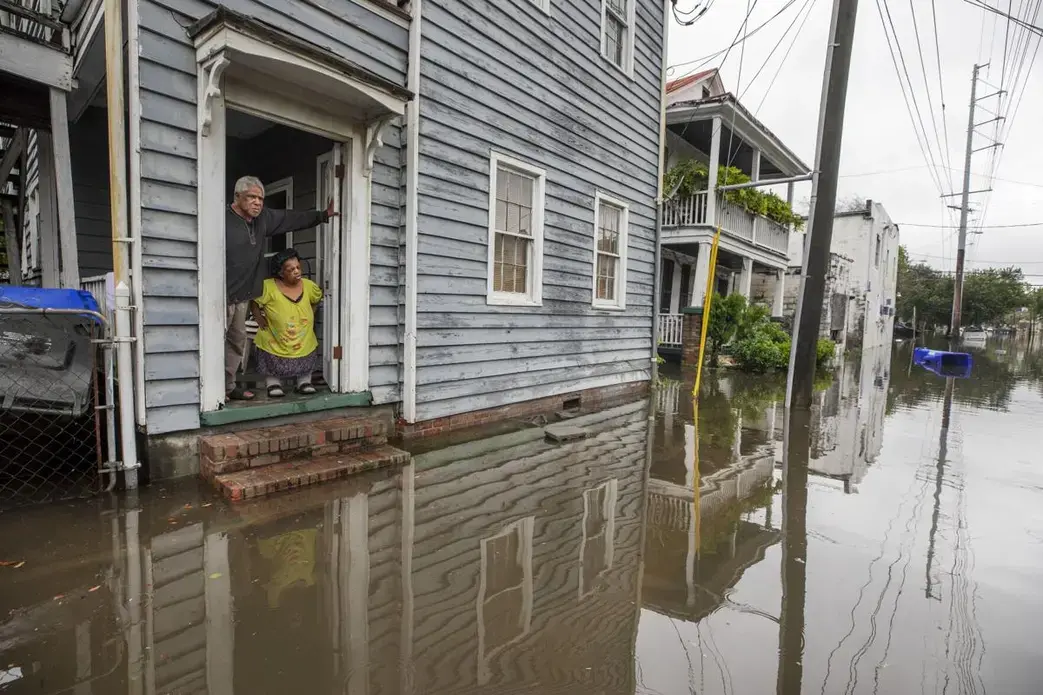 A man and woman look at flooding outside a home in Charleston, South Carolina.
