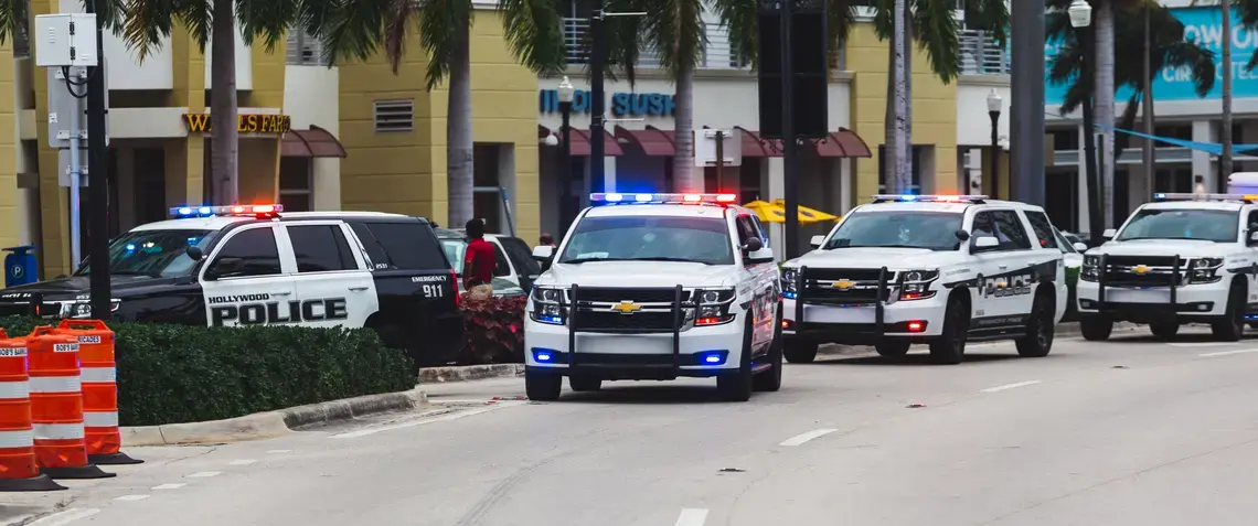 shutterstock_1751242514.jpeg Police vehicles line up on a road.