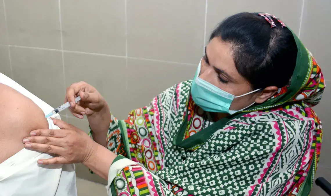 shutterstock_1963716649 copy.jpg A health worker in PPE gives someone a vaccine.