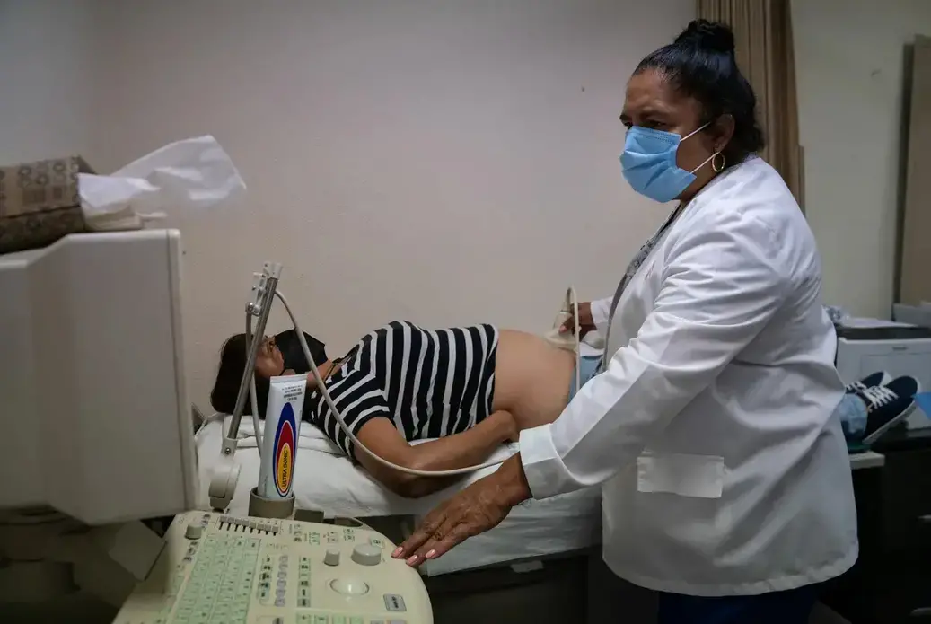 A doctor checks a patient's abdomen with an ultrasound machine