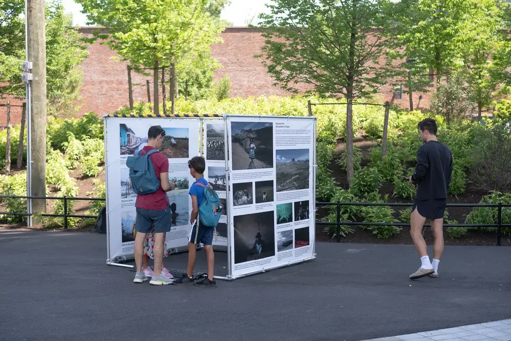 three people look at an outdoor photography exhibit