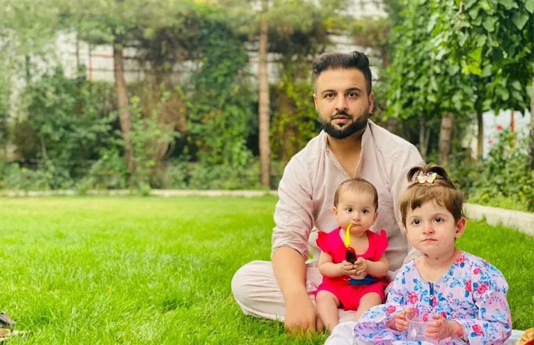 A father and his two daughters sit on the lawn