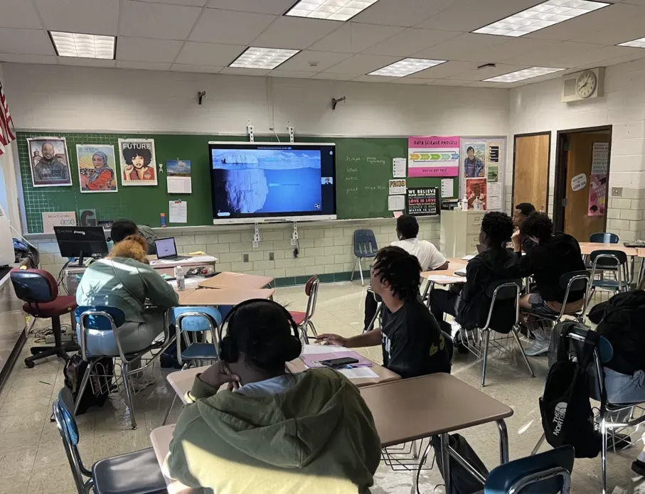 High school students seated in a classroom participate in a virtual journalist visit.