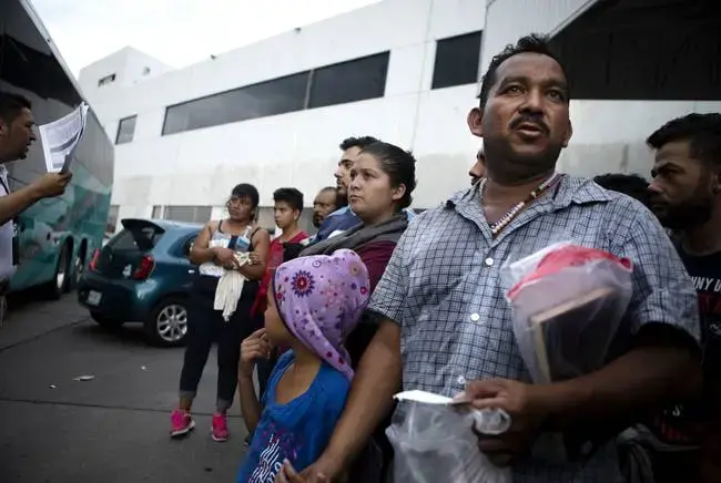 Migrants listen to a Mexican immigration official at a checkpoint in Nuevo Laredo. The group was returned to Mexico, and Mexican immigration officials planned to transport them to Monterrey, Nuevo León. Image by Miguel Gutierrez Jr. United States, 2019.