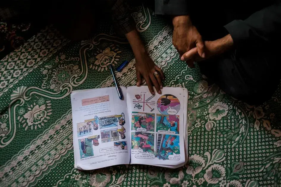 Salah uses a workbook to complete his English homework with his father. Image by Alex Potter. Yemen, 2018.