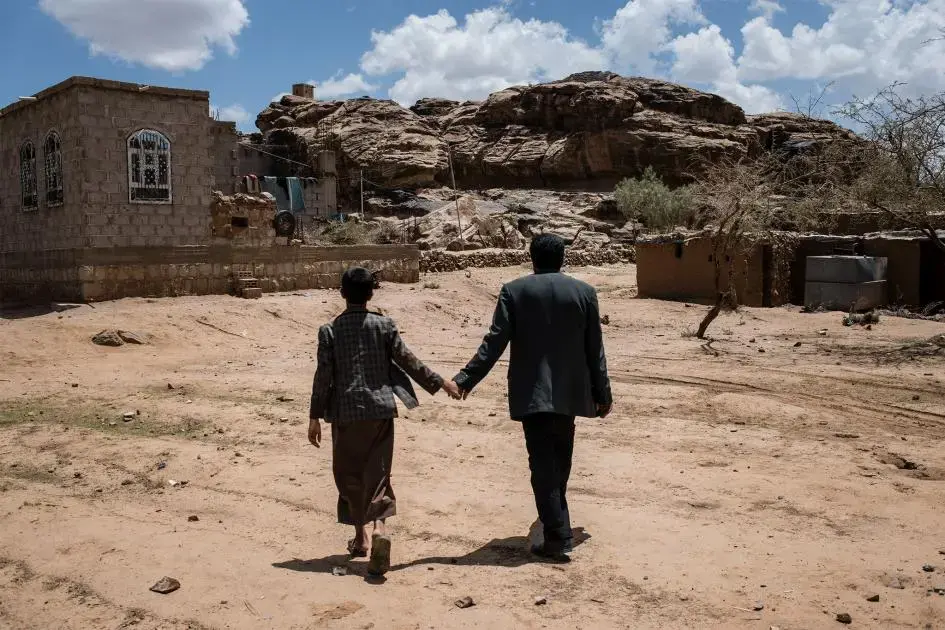 Salah and Yahya hold hands as they walk through a historic site near their home. Image by Alex Potter. Yemen, 2018.