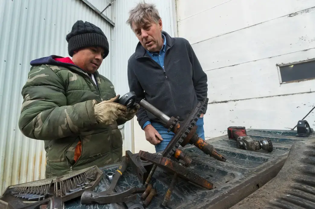Roberto Tecpile, left, a Mexican immigrant, replaces the bearings while repairing an irrigator with the help of dairy farm owner John Rosenow at Rosenholm Dairy in Cochrane. Image by Mark Hoffman. United States, 2019.