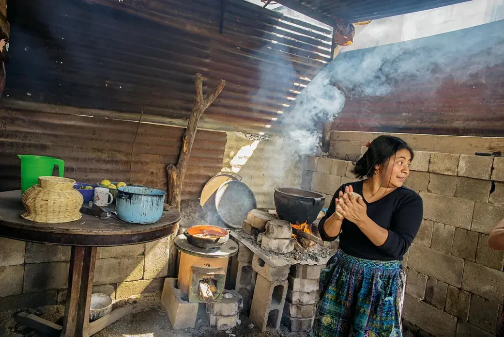 The new yellow stove is efficient, but the old open fire is better for the giant pot in Etelvina Pérez's kitchen in San Antonio Aguas Calientes. Image by Lynn Johnson. Guatemala, 2017.