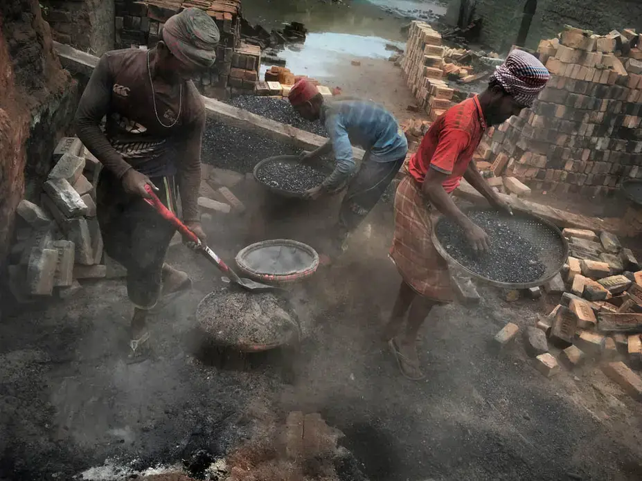 Here, laborers sift through the ashes of a previous kiln firing to prepare the area for a new batch of bricks. People who work in or live near brickfields with coal- or wood-fired kilns, one researcher estimates, are 10 to 20 times more likely to suffer lung diseases than those who don’t. Image by Larry C. Price. Bangladesh, 2018.