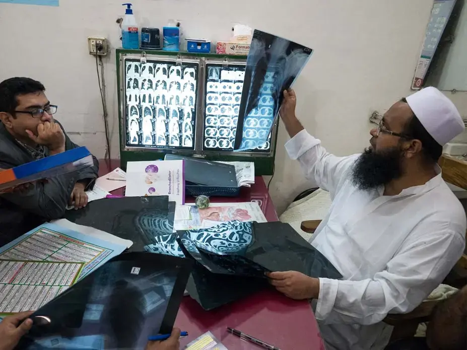 Dr. Ferdous Wahid, right, examines a chest x-ray. “This makes me alarmed,” one Dhaka resident said of the city’s pollution, “thinking how much of the dust is settling in my lungs.” Image by Larry C. Price. Bangladesh, 2018.