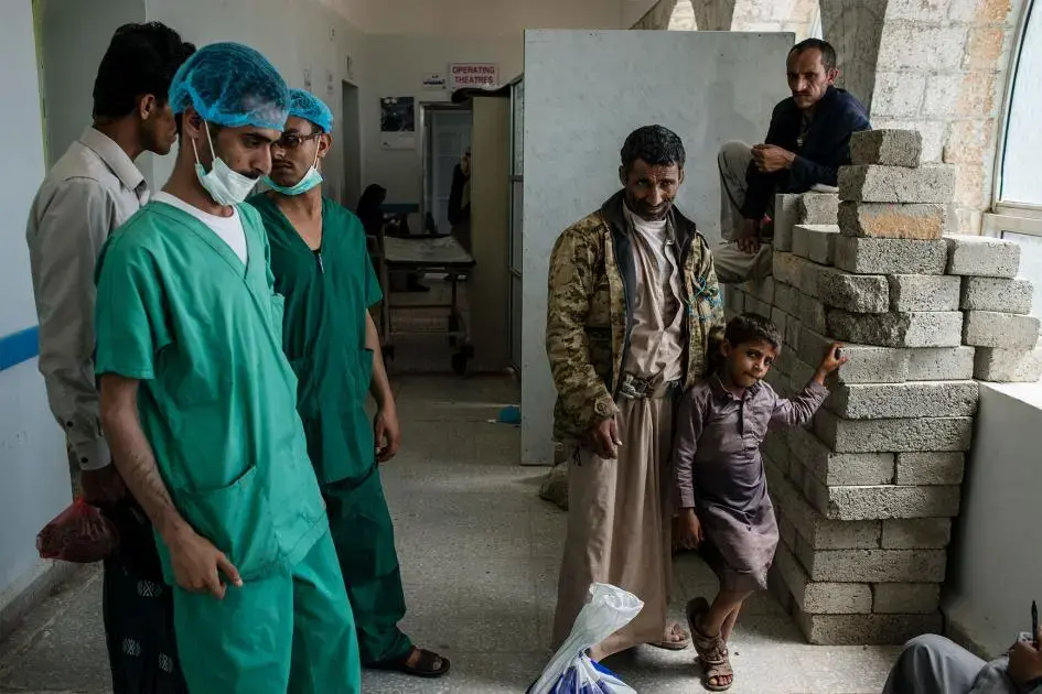Rasheed (center) talks with doctors about his son's medical care. He and his son traveled eight hours to visit the facility. Image by Alex Potter. Yemen, 2018.