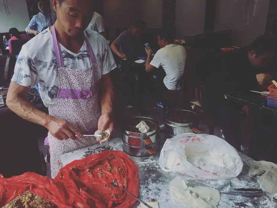 A man makes dumplings at a restaurant serving breakfast on Sunday, Sept. 24, 2017, in Beijing, China. The dumplings were assembled in the doorway and cooked in the street. Image by Kelsey Kremer. China, 2017.