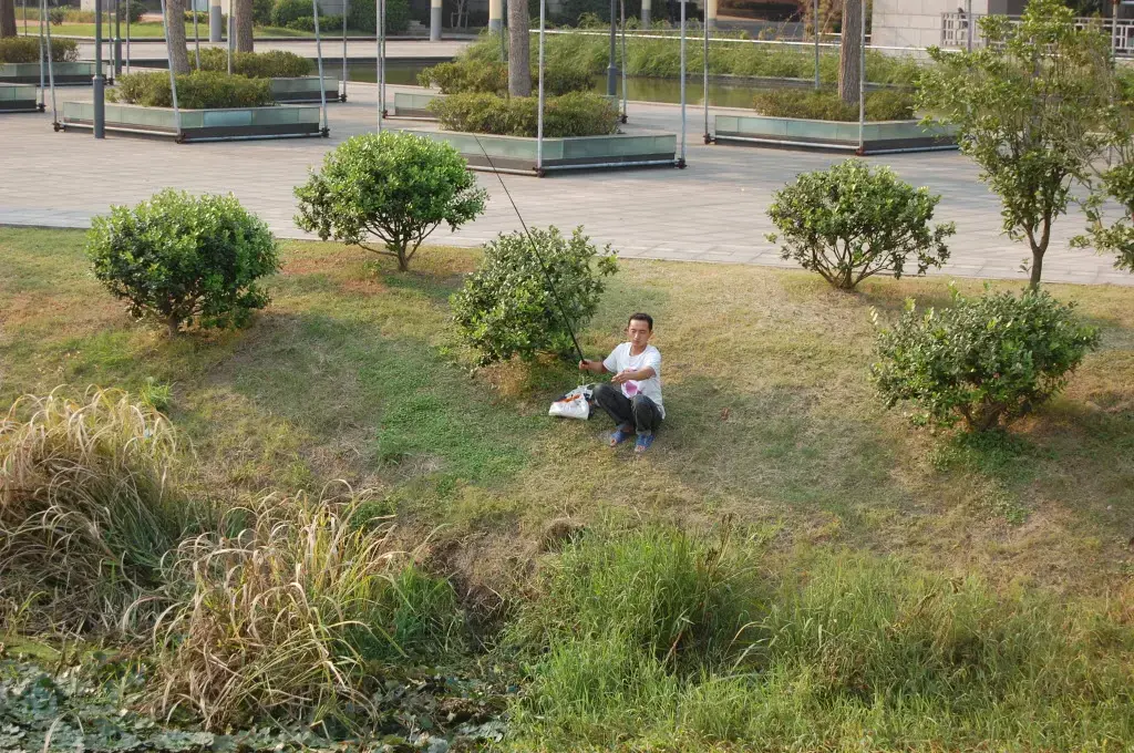 A man fishes outside the office of the "Wuxi 530" incentive program which has brought dozens of foreign-educated Chinese scientists to the city, drawn by generous grants and rent free business space. The city of 5 million people is unknown outside China, but it is seeking to escape its national image as one of the worst polluters in China. The city's prosperous chemical factories on the shore of Lake Tai, the third largest freshwater lake in China, have released so much pollution that in 2007, nearly 2 million people here were deprived of cooking and drinking water for a week when a thick layer of green scum formed over the lake. Image by Peter Ford. China, 2012. Media file: AX049_6599_9.JPG