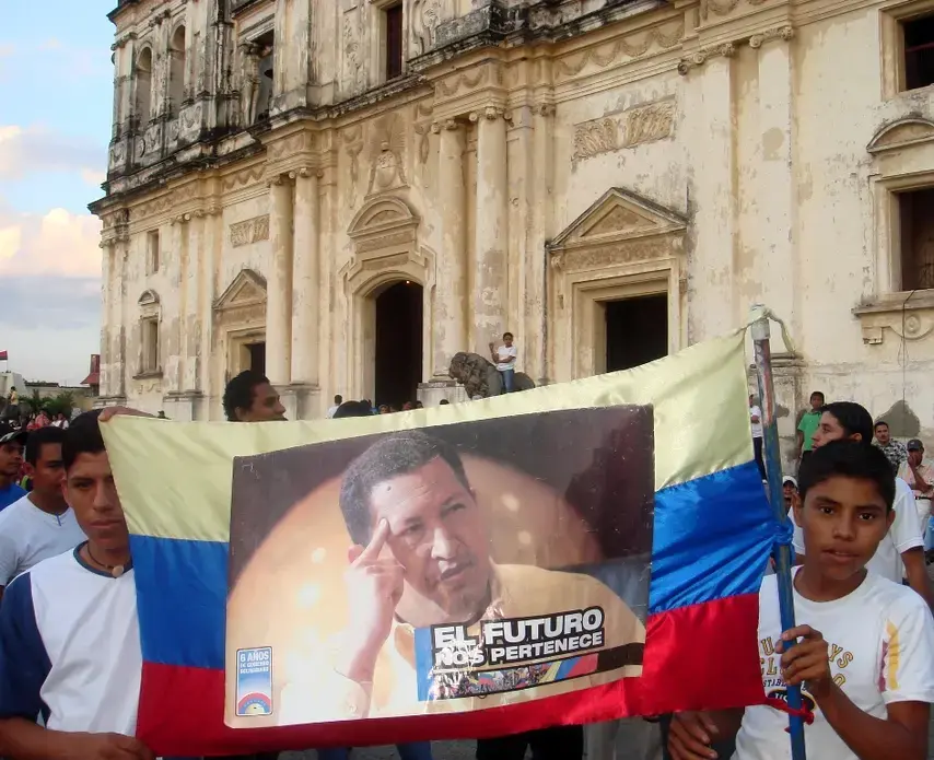 Young Nicaraguan Sandinistas hold a sign of support for Venezuelan President Hugo Chavez outside the cathedral in León, Nicaragua. Image by Tim Rogers. Nicaragua, 2012. Media file: Chavez sign Leon.jpg
