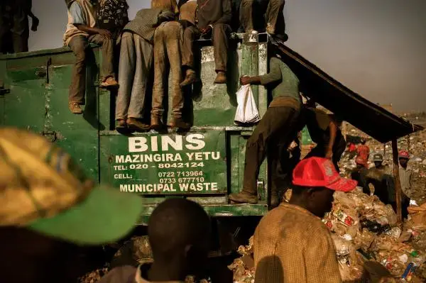 Men pick through a waste bin and the garbage pile at the 30-acre Dandora dump in Nairobi, Kenya, in a search for food scraps and salable refuse. A controversial effort is under way to relocate the dump. Image by Micah Albert. Kenya, 2012. Media file: Dandora-5_2.jpg