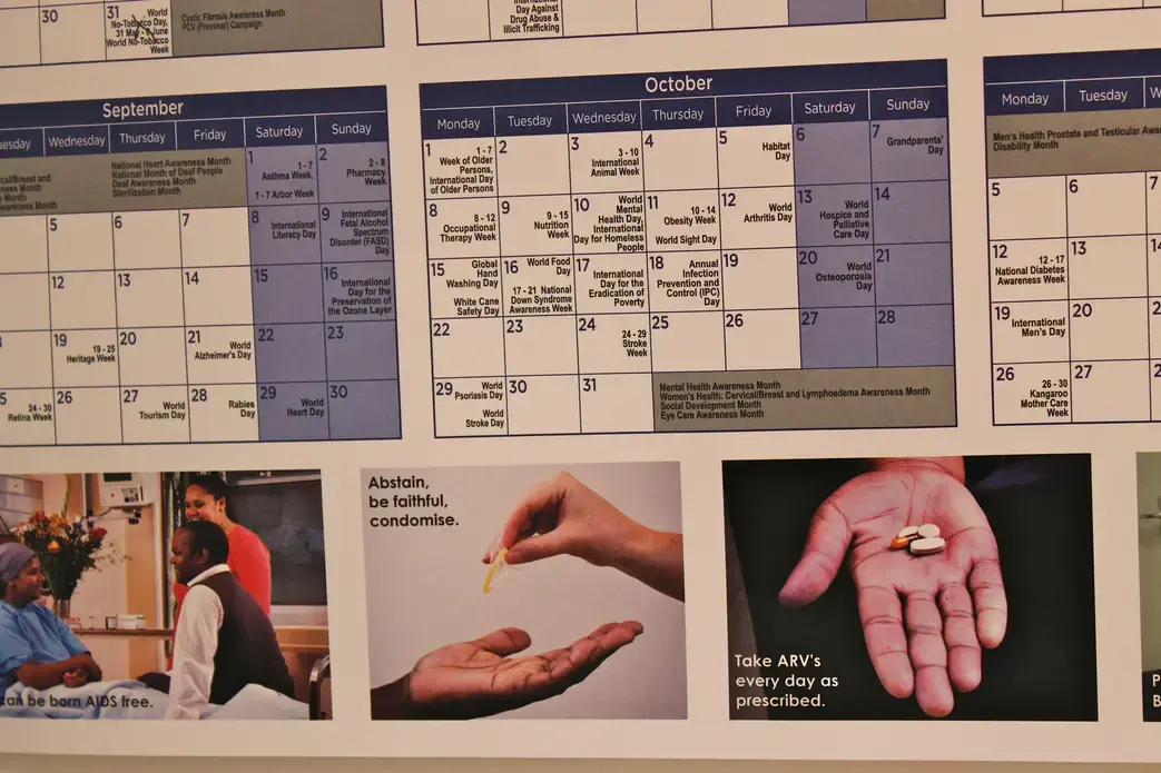 A calendar in the office of an HIV/AIDS non-profit organization reminds those living with the condition to take their medicine on time and to use preventive sexual measures. Once a death sentence, HIV is now a manageable disease. Image by Melissa Turley, South Africa, 2012. Media file: IMG_2653.JPG
