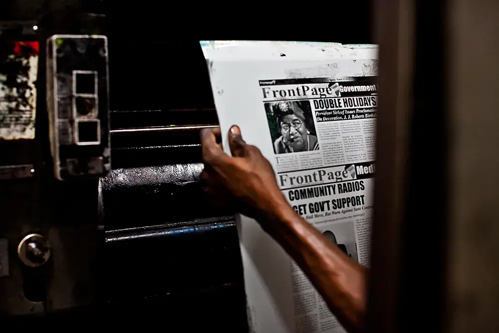 A man holds the inked plate for FrontPage Africa's front page. A story on female genital mutilation that ran in the paper resulted in threats against the author, Pulitzer Center grantee Mae Azango. Image by Jake Naughton. Liberia, 2012. Media file: Jina-blog-image.jpg