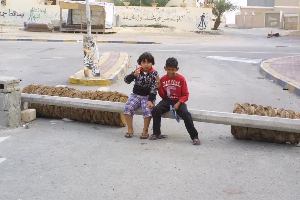Youngsters sit atop a barricade erected by Muhazza Villagers to keep out security forces. Image by Reese Erlich. Bahrain, 2012. Media file: Kids roadblk 2.JPG