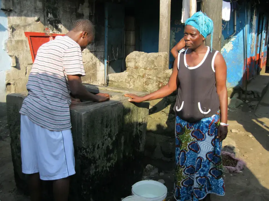 Kulah Borbor, whose husband died of cholera, at the well she uses in West Point, a slum in Monrovia, Liberia. Image by Peter Sawyer. Liberia, 2011. Media file: Kulaborbor.jpg