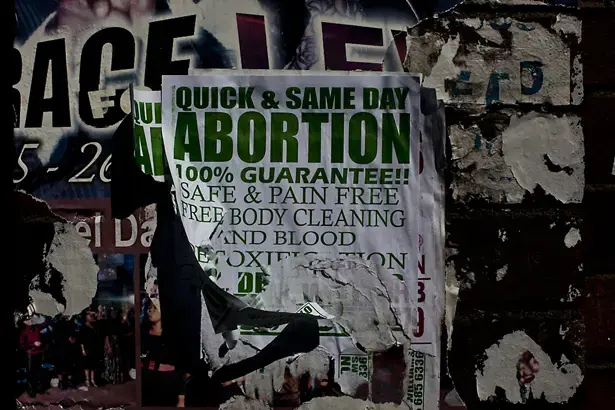 In today's South Africa, it is often easier and cheaper to get an illegal abortion than a legal one. Across the street from the Hillbrow clinic in Johannesburg, a brick apartment building is plastered with neon-colored posters advertising fast, cheap and confidential services. Image by Jake Naughton. South Africa, 2012. Media file: SA_Abortion_img.jpg