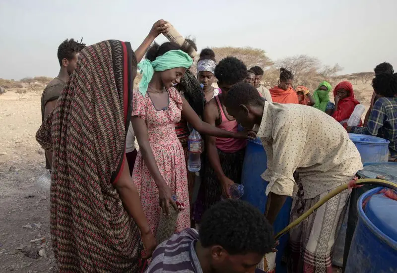 Ethiopian Tigray migrants in Obock, Djibouti, stand in line to receive water brought by smugglers, as they take shelter under trees at the last stop of their journey before leaving by boat for Yemen in the evening, July 15, 2019. Image by AP Photo / Nariman El-Mofty. Djibouti, 2019.
