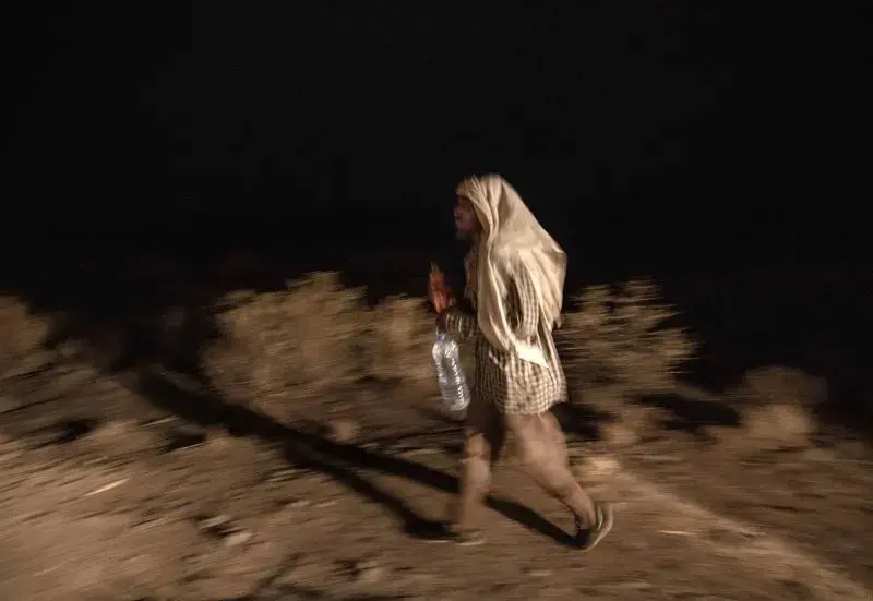 Ethiopian migrant Mohammed Eissa, 35, walks along a highway, about 50 kilometers (31 miles) from Djibouti, July 12, 2019. Eissa picked up rides from his home to the border with Djibouti, then walked. His second day there, he was robbed of his money at knifepoint. The next day he walked six hours in the wrong direction, back toward Ethiopia, before he found the right route again. Image by AP Photo / Nariman El-Mofty. Djibouti, 2019.