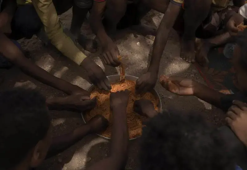 Ethiopian migrants eat spaghetti as they take shelter under a tree, in Obock, Djibouti, July 15, 2019. Image by AP Photo / Nariman El-Mofty. June, 2019.