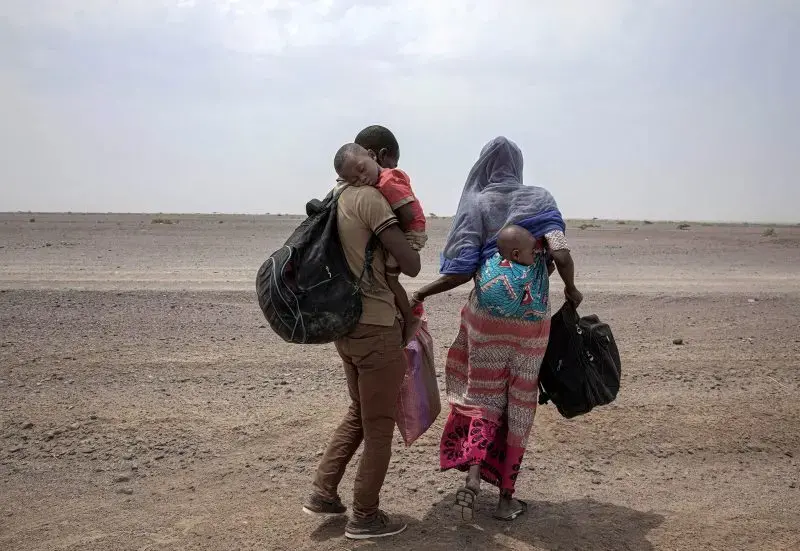 Fatma and her husband Yacoub, migrants from Mali, carry their children as they make their way in Lahj, Yemen, July 23, 2019. Image by AP Photo / Nariman El-Mofty. Yemen, 2019.