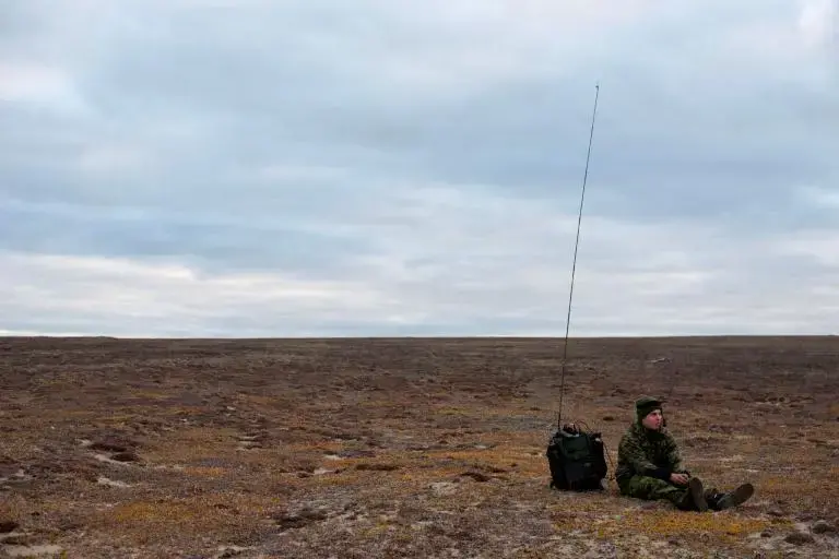 A soldier waits by his radio on the tundra near Blue Fox Harbor on Banks Island in the Canadian Arctic. The soldier was part of Operation Nanook, an annual “sovereignty operation,” in which Canadian forces patrol the nation’s northern territory. Image by Louie Palu. Canada, 2018.