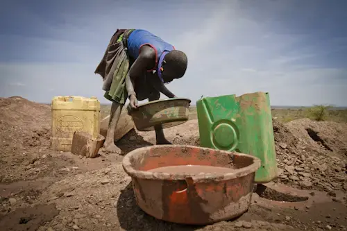 A Karamojong girl tries to extract gold from the earth that her partner has mined from one of the many pits scattered on the slopes of Mount Moroto at Rupa. Image by Marc Hofer. Uganda, 2011. image