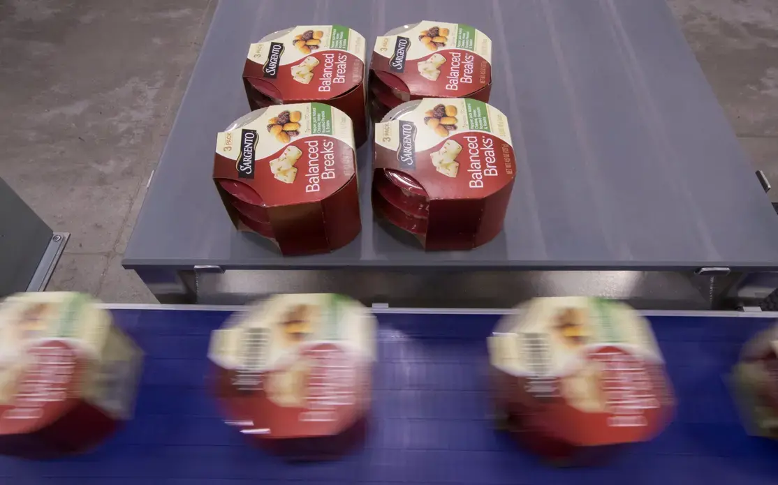 Kathy Griffey, top, and Kristin Geary, bottom right, work on an assembly line packaging Balanced Breaks snacks at Sargento Foods Inc. The company employs about 2,300 people in Wisconsin. Image Courtesy of Mark Hoffman. United States, 2019.