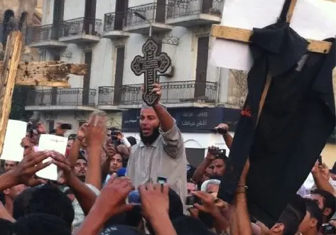 Islamist holds up cross and leads crowd in chants against military council. Image by Sharif Abdel Kouddous. Egypt, 2011. Media file: cairocopticchristian.jpg