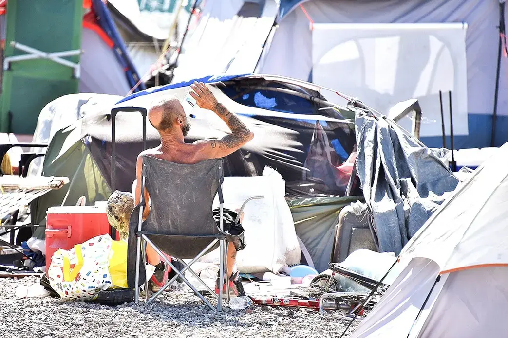 A homeless man sits by his belongings at the Lots, an outdoor encampment in Phoenix, on June 24. Summer temperatures in Phoenix consistently exceeded 110 degrees Fahrenheit, sometimes hitting 118. Image by Steve Carr/Human Services Campus. United States, 2020.