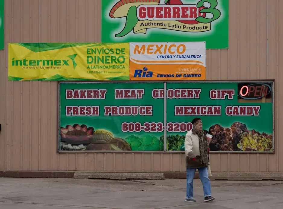 A pedestrian walks past one of a number of businesses that cater to Mexican immigrants in Arcadia in western Wisconsin. Image by Mark Hoffman. United States, 2019.