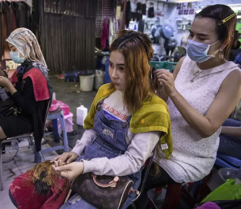 Hair salon owner Meyly Heng places a hair extension on a customer in Phnom Penh. Image by Paula Bronstein. Cambodia, 2019. Hair salon owner Meyly Heng places a hair extension on a customer in Phnom Penh. Image by Paula Bronstein. Cambodia, 2019.