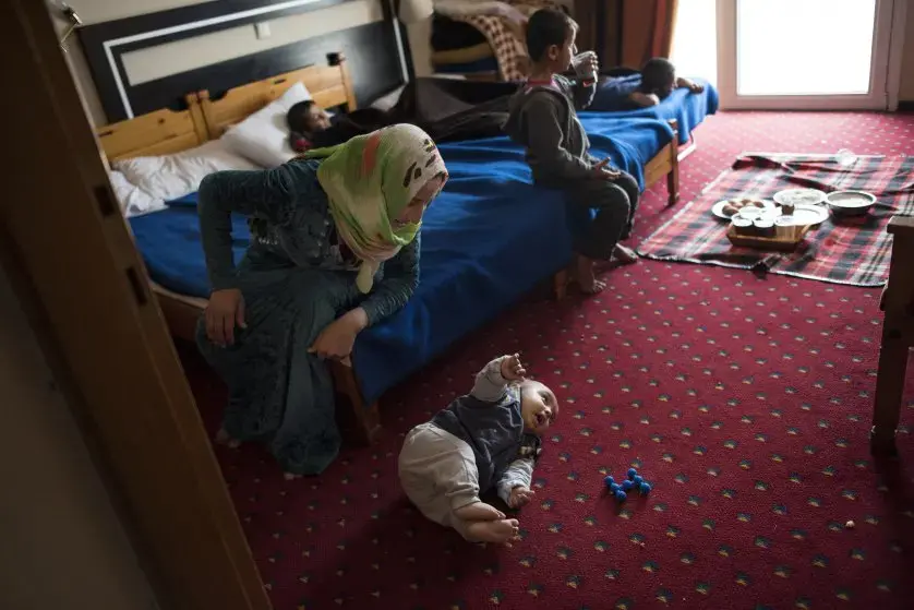 27-year-old Illham Saleh watches her six-month-old baby, Faraj, try to roll over while at a hotel in Kastoria, Greece, near the Albanian border. Image by Lynsey Addario. Greece, 2017.