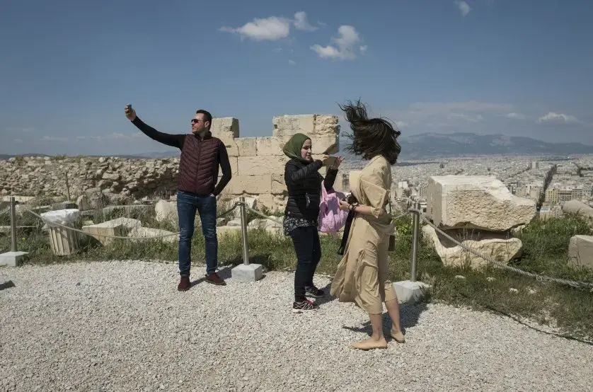 Syrian refugee, Taima, takes photographs among other tourists while visiting the Acropolis in Athens. Image by Lynsey Addario. Greece, 2017.