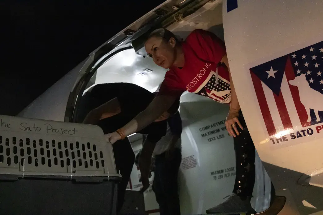 Beckles reaches out of the plane door to grab the next crate and stack it. Image by Jamie Holt. United States, 2019.