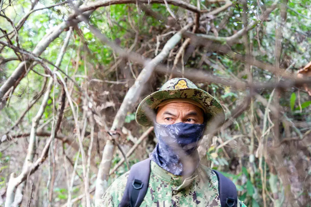 A Cambodian environmental ranger on patrol looking for illegal loggers in the Phnom Tnout Phnom Pok sanctuary. Some rangers hide their identity out of fear of reprisals from loggers and their allies in the police and military. Image by Sean Gallagher. Cambodia, 2020.<br />

