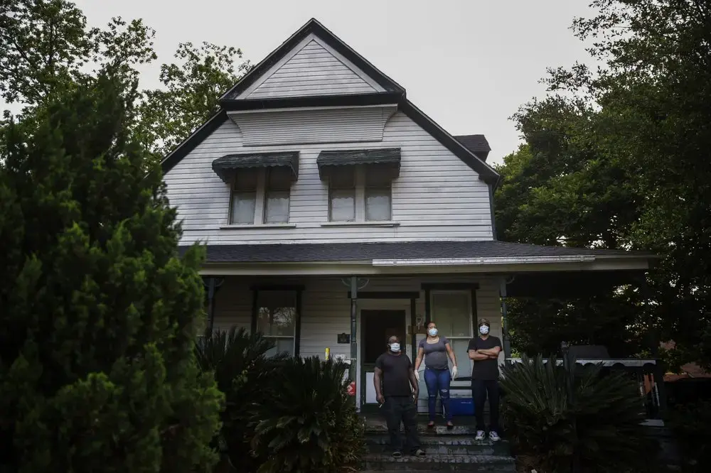 Erick Brown, left, Saundra Brown, center, and George Savage, right, stand on their porch while social distancing and wearing protective masks amid the COVID-19 coronavirus outbreak on Friday, April 17, 2020, in Dawson, Ga. Image by Brynn Anderson / AP Photo. United States, 2020.