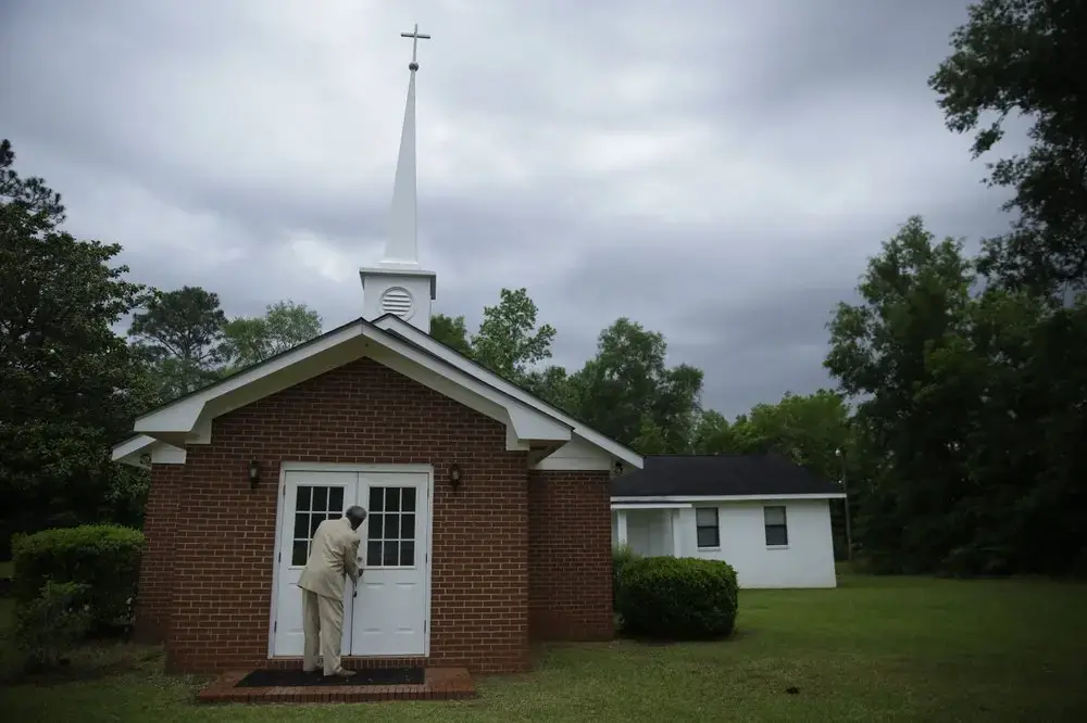 Eddie Keith, 65, of Dawson, Ga., locks the church doors as he leaves on Sunday, April 19, 2020, in Dawson, Ga. He visits his pastor's church a couple times a week. Keith says as he loaded the body of his pastor into the hearse, he talked to him, 'I didn't think you'd leave me so early,' he remembers saying. 'I thought we were going to grow old together.' Image by Brynn Anderson / AP Photo. United States, 2020.