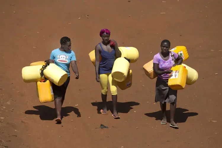 Women carry water jugs outside a facility where residents can buy clean drinking water in the Kawangware slum. Image by Mark Hoffman. Kenya, 2017. 