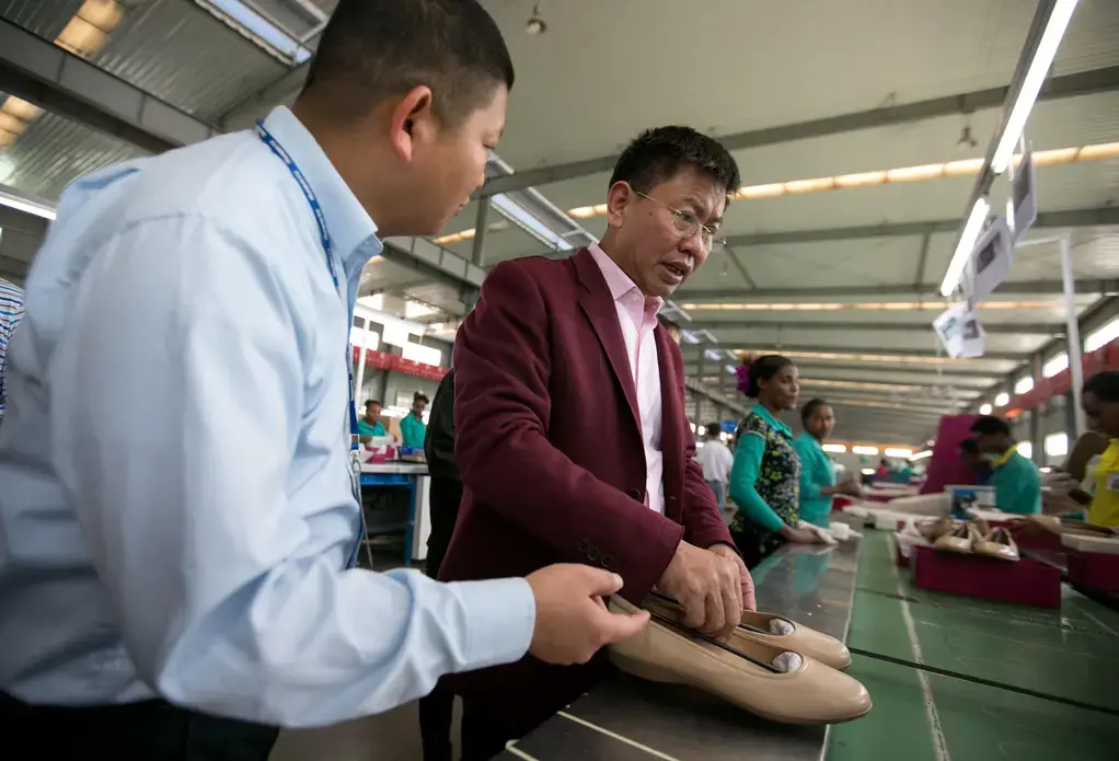 Zhang Huarong, chief executive of Huajian Shoe Co., inspects the production lines. Left, in the Chinese-owned Huajian Shoe Co. Factory in Addis Ababa, more than 6,000 workers build shoes for American brands such Tommy, Guess and Lucky. Image by Noah Fowler. Ethiopia, 2017.