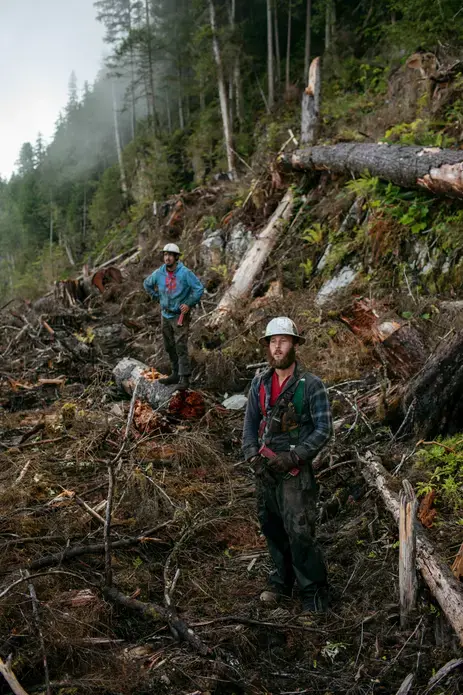Drew Newman, wearing red suspenders, and Will Karl, in a blue sweatshirt, prepare at the Tuxekan logging site. Image by Joshua Cogan. United States, 2019.