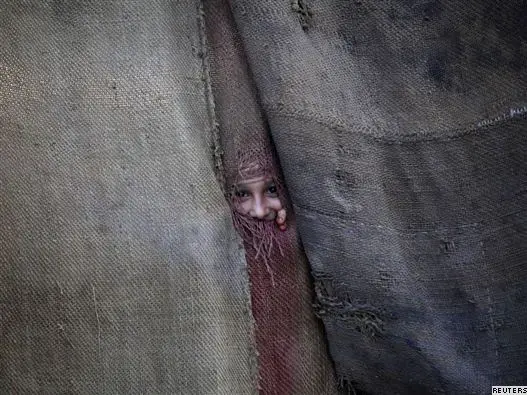 A Pashtun girl peeks through the doorway to her family dwelling in Peshawar. Image by Shaheen Buneri. Pakistan, 2011. image