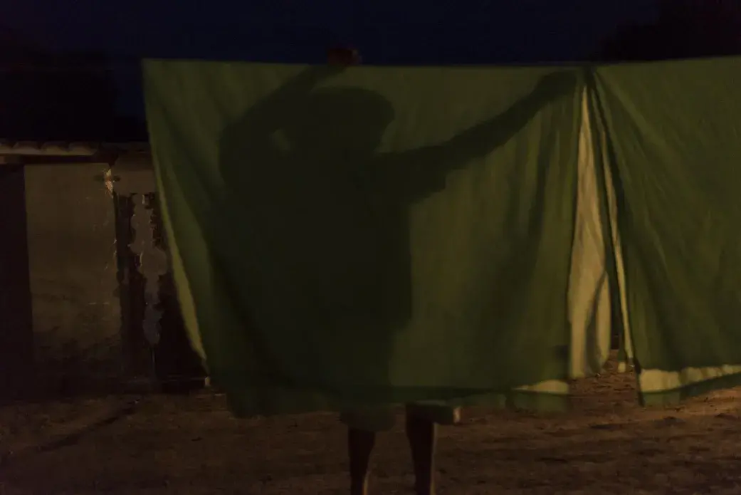 Juan Carlos Salazar hangs wet sheets to dry at the hotel and cultural center that his family maintains in Tarata, Bolivia. Juan Carlos lived in the United States for 12 years as a construction worker before he returned to his hometown of Tarata. “I could live on the moon or Mars as long as there is work,” he said. He will go wherever he can work to provide for his wife and four children. Image by Carey Averbook. Bolivia, 2016.