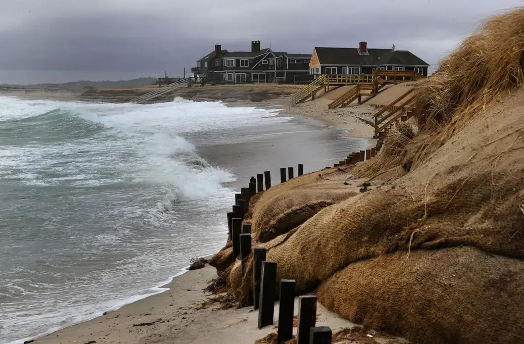 During a nor'easter, surf washed up close to the dunes where homes stand facing Town Neck Beach. Image by John Tlumacki. United States, 2019.