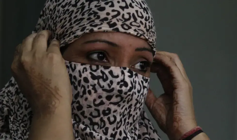 In this Thursday, Oct. 31, 2019, photo, Amandeep Kaur, a former tramadol user, covers her face at the de-addiction at center in Kapurthala, in the northern Indian state of Punjab. Kaur was pregnant when her husband died of a heart attack. She turned to the sex trade to make ends meet. She wanted not to feel, and a fellow sex worker suggested tramadol. She had no idea she’d get addicted, but eventually needed three pills to get through the day. “If I didn’t have it I felt lifeless, my body ached as if I was going to die,” she said, and joined the line stretching from the addiction clinic’s doors. Image by Channi Anand / AP Photo. India, 2019.