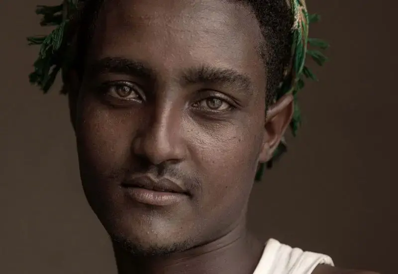 Hussein Asfar, 20, a migrant from Ethiopia who was a victim of physical abuse when he landed in Yemen, poses for a portrait in the 22nd May Soccer Stadium, destroyed by war and serving as a temporary refuge for thousands of migrants in Aden, Yemen, July 21, 2019. Image by AP Photo / Nariman El-Mofty. Yemen, 2019.