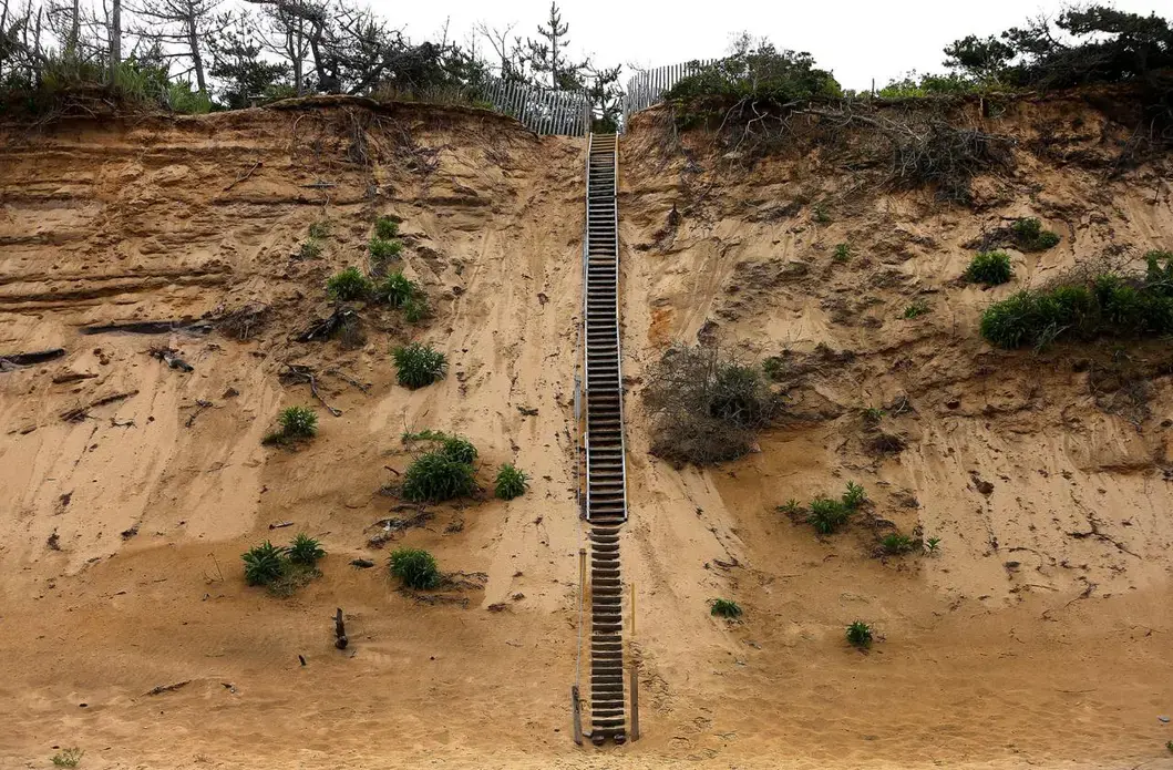 A long wooden staircase led to the top of an eroding sand cliff at Lecount Hollow Beach in Wellfleet. Image by John Tlumacki. United States, 2019.